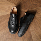 Black leather sneakers, side and heel view showing lace-up and platform rubber sole