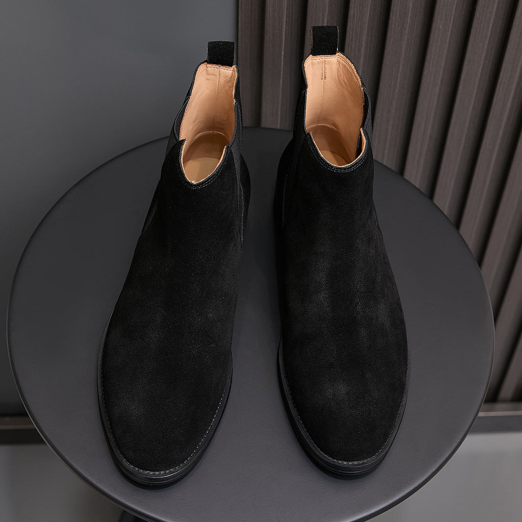 Black suede Chelsea boots with pointed toe, elastic side panels, and tan-lined interior