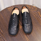 Men's black leather sneakers with laces and side panels, on a wooden surface