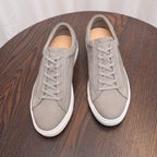 Gray suede leather sneakers on tabletop, lace-up with white rubber soles