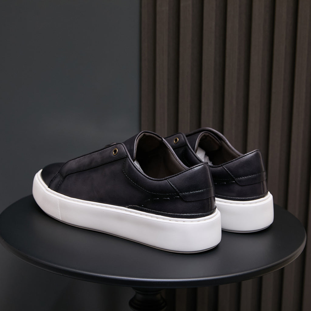 Black leather sneakers from heel view with white rubber sole and low profile