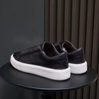 Black leather sneakers from heel view with white rubber sole and low profile
