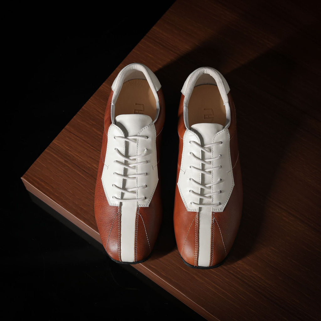 Men’s leather sneakers, brown and white panels, lace-up design on wooden surface