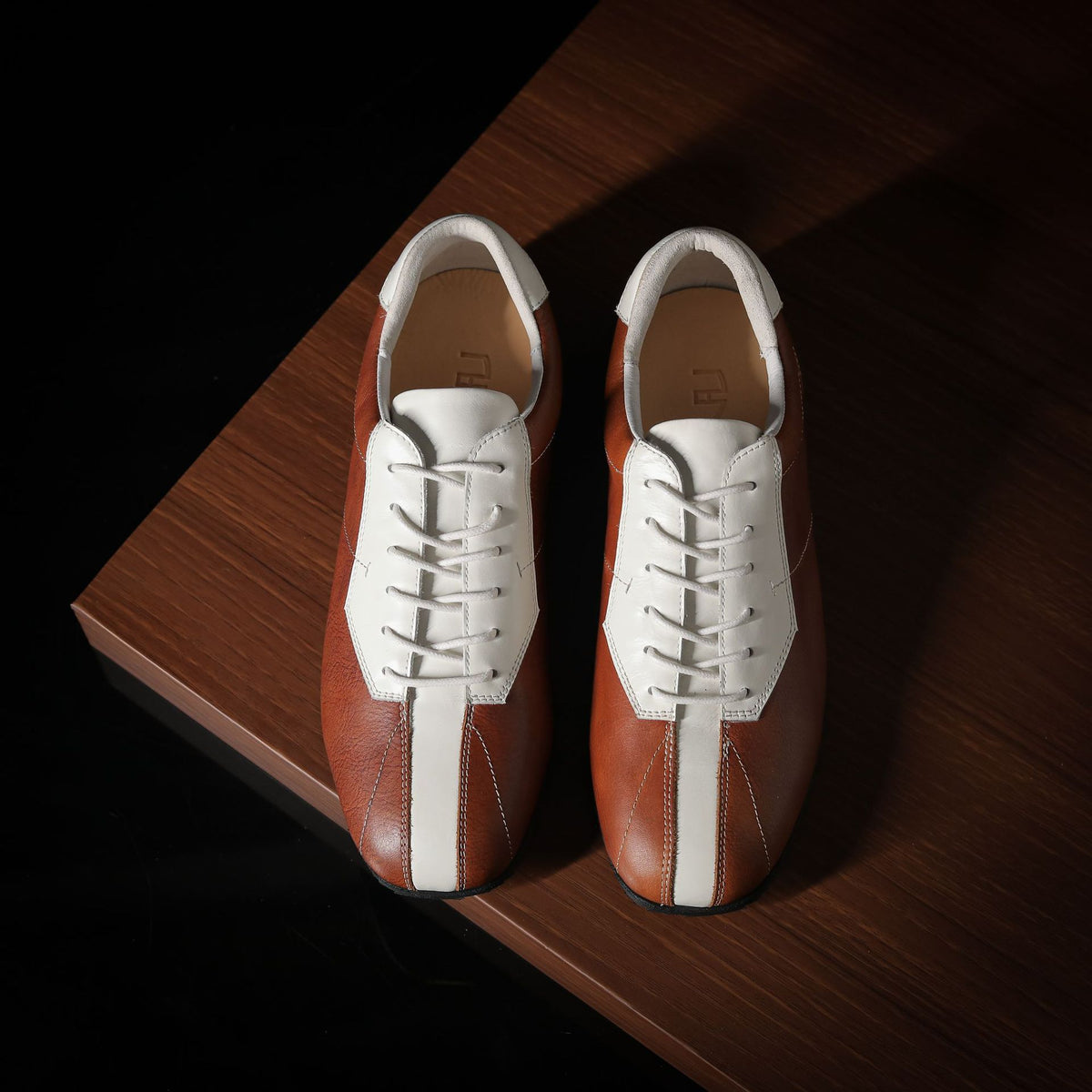 Men’s leather sneakers, brown and white panels, lace-up design on wooden surface