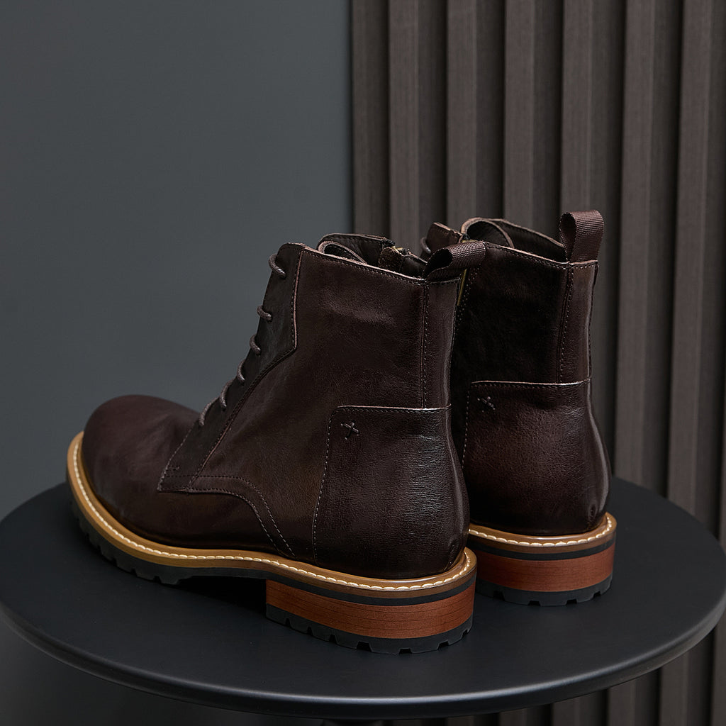 Dark brown leather boots with side zip panels, lace-up front, and rugged lug outsole