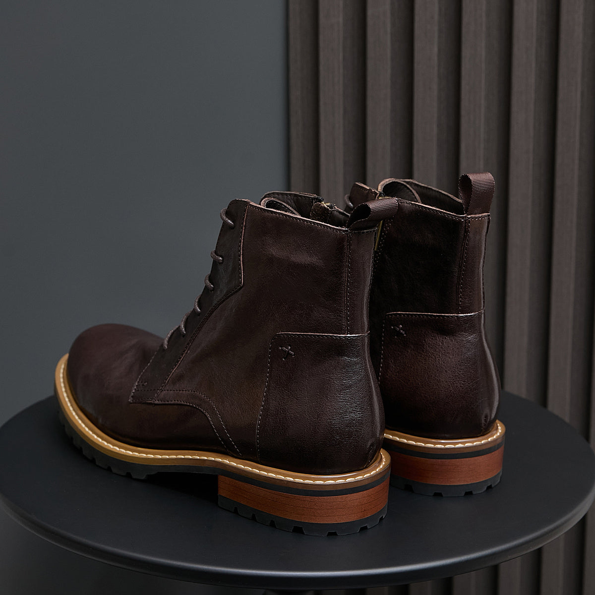 Dark brown leather boots with side zip panels, lace-up front, and rugged lug outsole