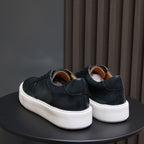 Dark blue leather sneakers rear view, white rubber soles and heel tab.