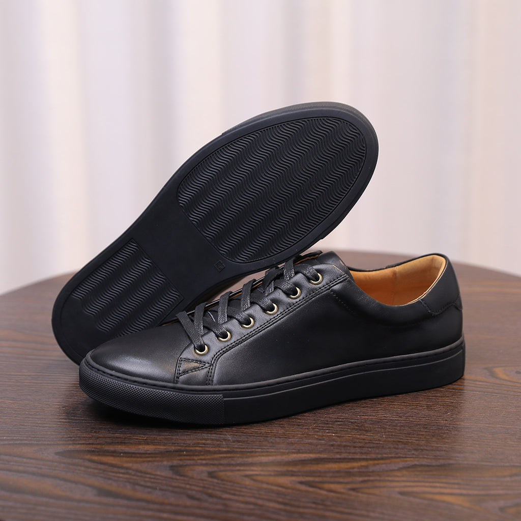 Men's genuine leather sneakers, black, outsole and toe view on a wooden table.