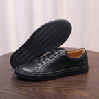 Men's genuine leather sneakers, black, outsole and toe view on a wooden table.