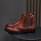Men's pointed-toe Chelsea dress boots in dark brown, angled side view with pull tabs
