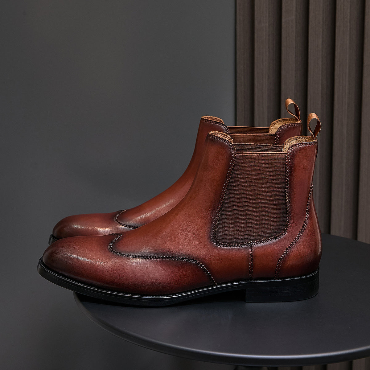 Men's pointed-toe Chelsea dress boots in dark brown, angled side view with pull tabs