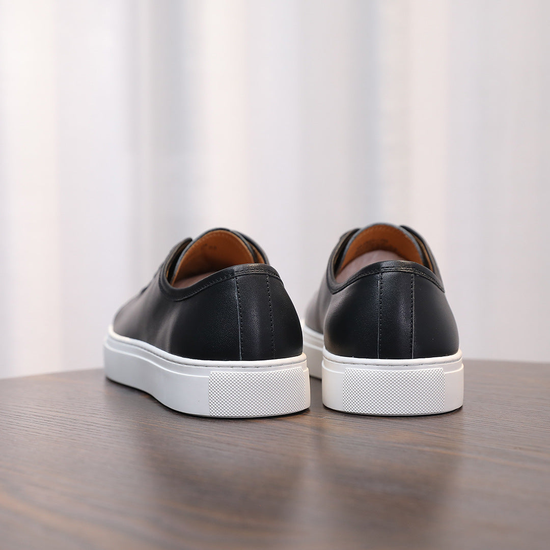 Black leather sneakers with white textured heel and rubber outsole, rear view.