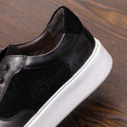 Black leather sneakers close-up at side and toe, stitched panels, white sole