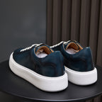Back view of blue leather low-top sneakers with white midsoles and heel tabs