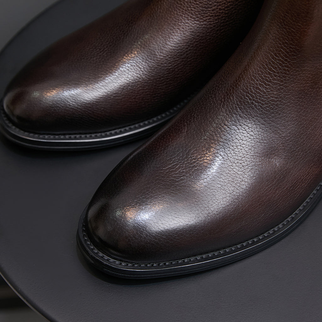 Men's pointed-toe Chelsea boot toe with stitched trim, dark brown upper
