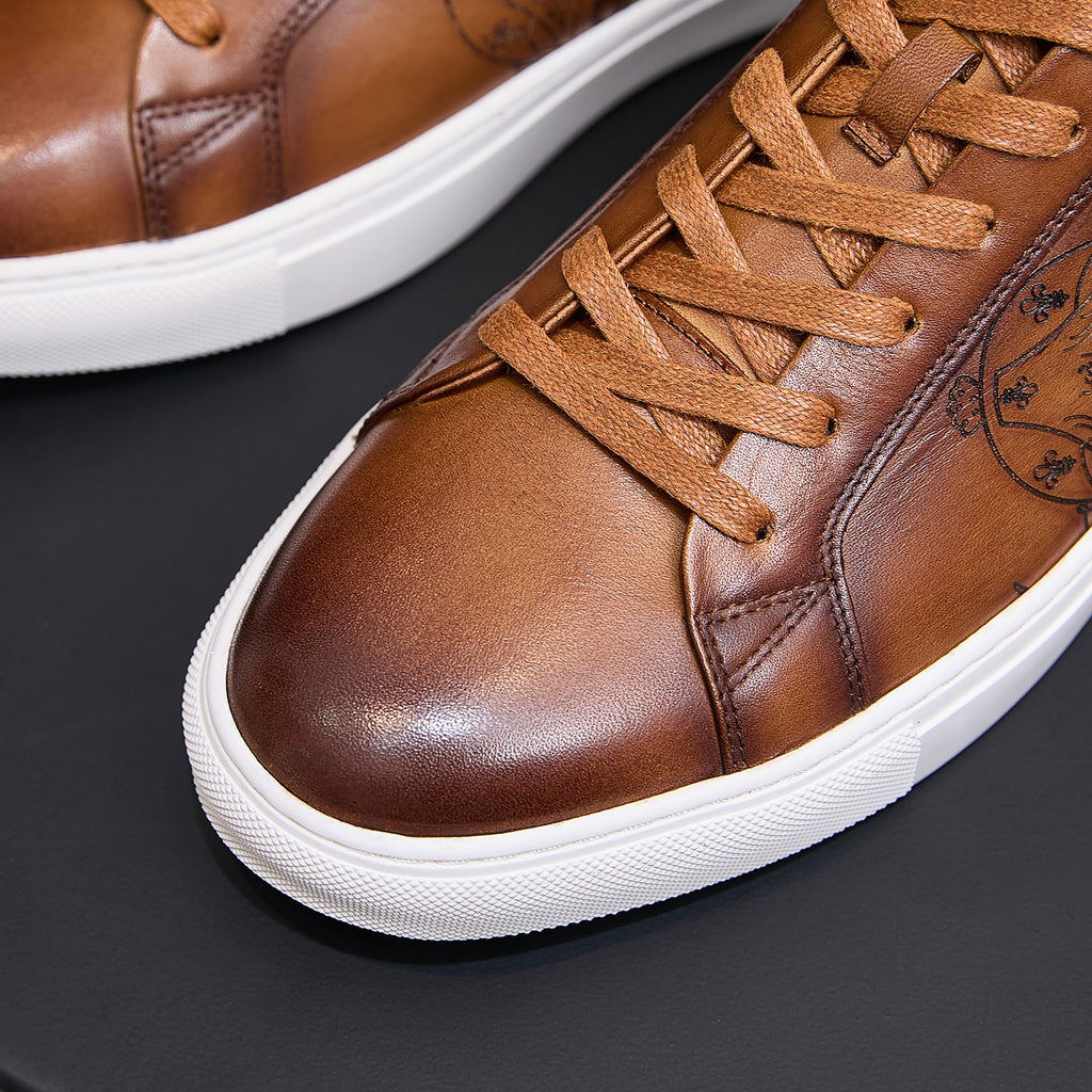Men's tan leather sneakers close-up with lace-up front and embossed side panel