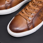 Men's tan leather sneakers close-up with lace-up front and embossed side panel