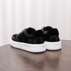 Black leather low-top sneakers, heel view with white rubber sole and lace ties
