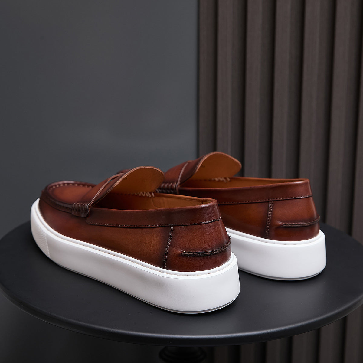 Men's brown leather slip-on sneakers rear quarter view with white cushioned platform sole.