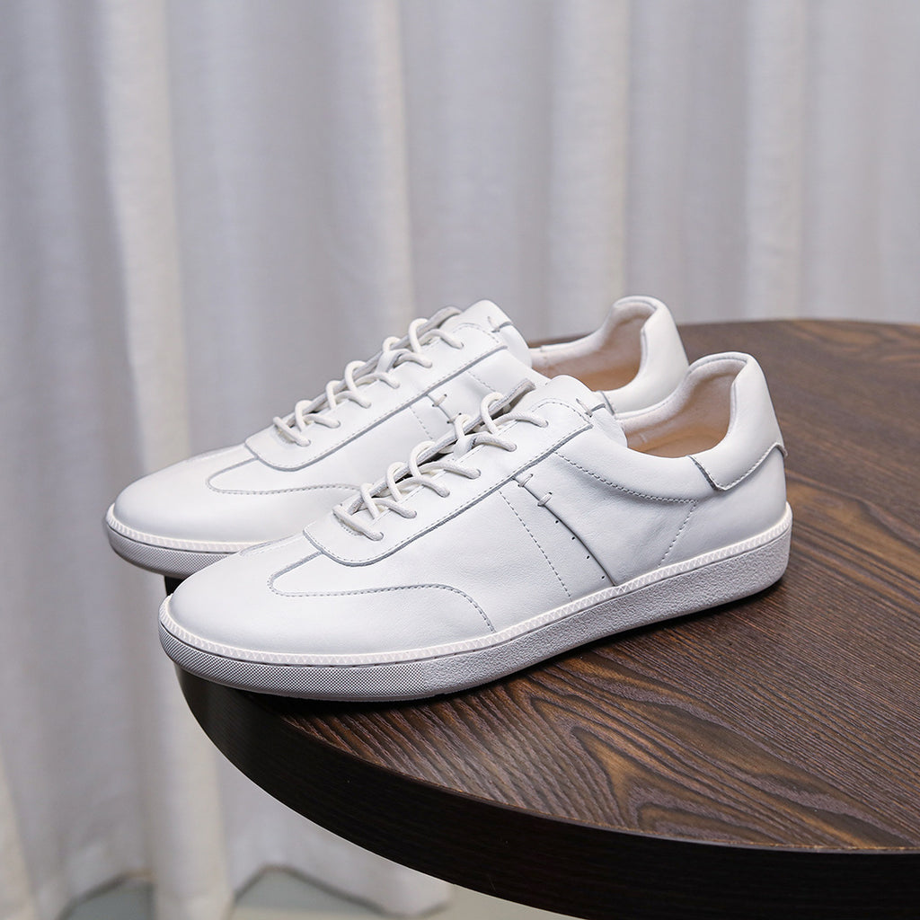 White leather lace-up sneakers with stitched panels and white rubber sole.