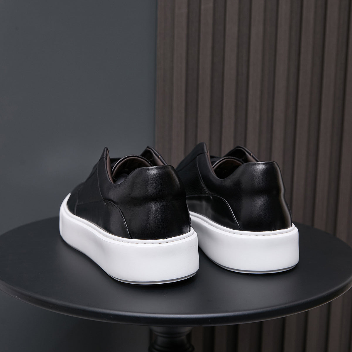 Men's genuine leather sneakers in black, rear view with white midsole platform.