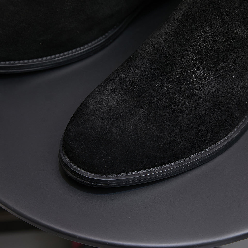 Close-up of black suede pointed toe Chelsea boot with dark rubber sole edge