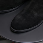 Close-up of black suede pointed toe Chelsea boot with dark rubber sole edge