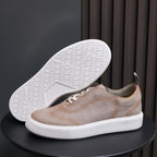 Light taupe leather sneakers with white outsole tread showing underfoot