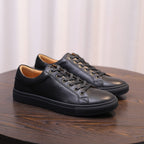 Men's genuine leather sneakers, black lace-up low-tops, angled pair view.
