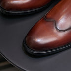 Men's pointed-toe Chelsea dress boot, close-up of glossy dark brown vamp and stitching