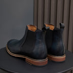 Pair of dark blue Chelsea dress boots with pull tabs, side elastic, and wood-tone sole