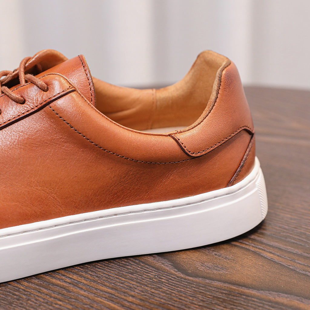 Brown genuine leather men's sneaker with white rubber sole and lace-up front.