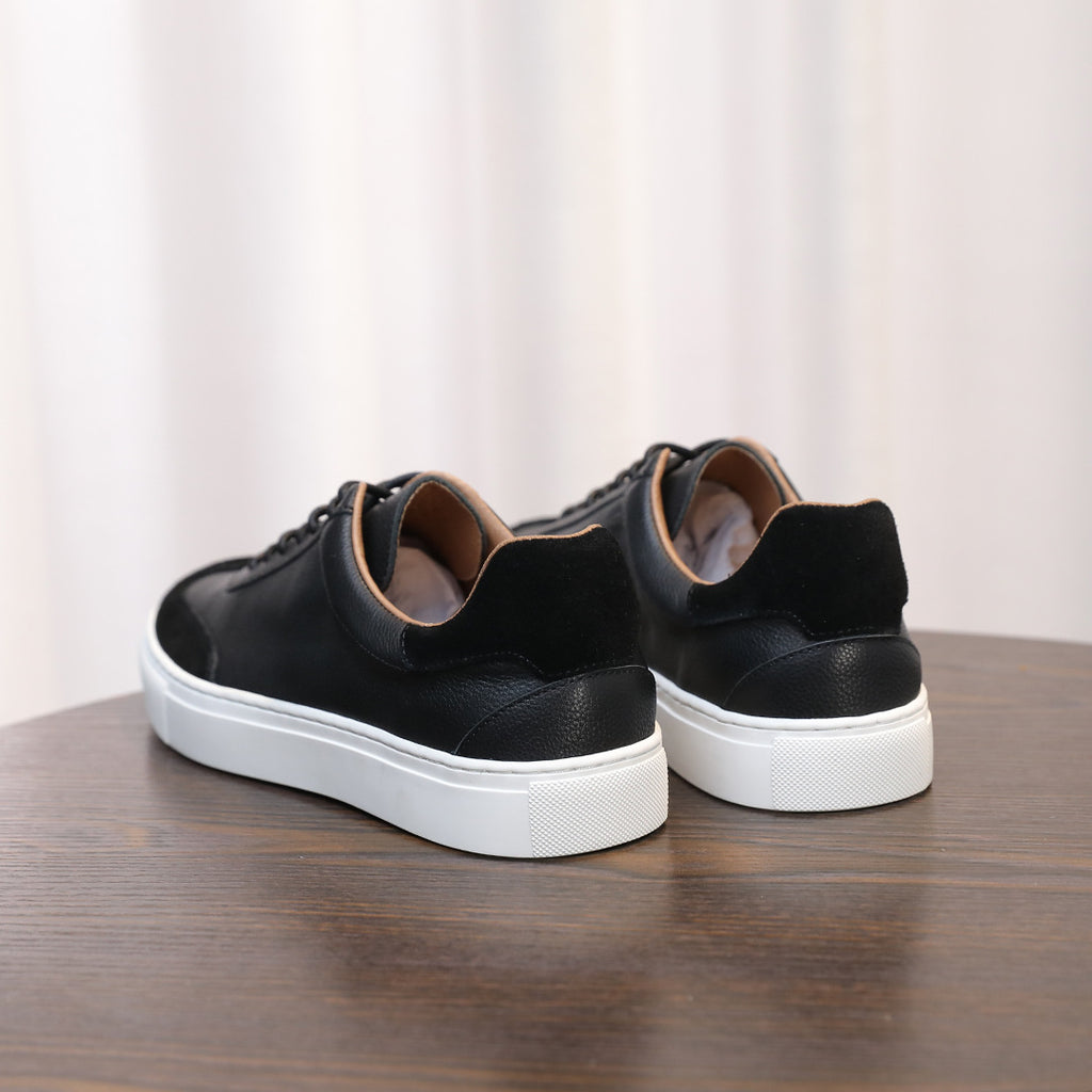 Men's black leather sneakers, rear view showing heel tab and white rubber sole.