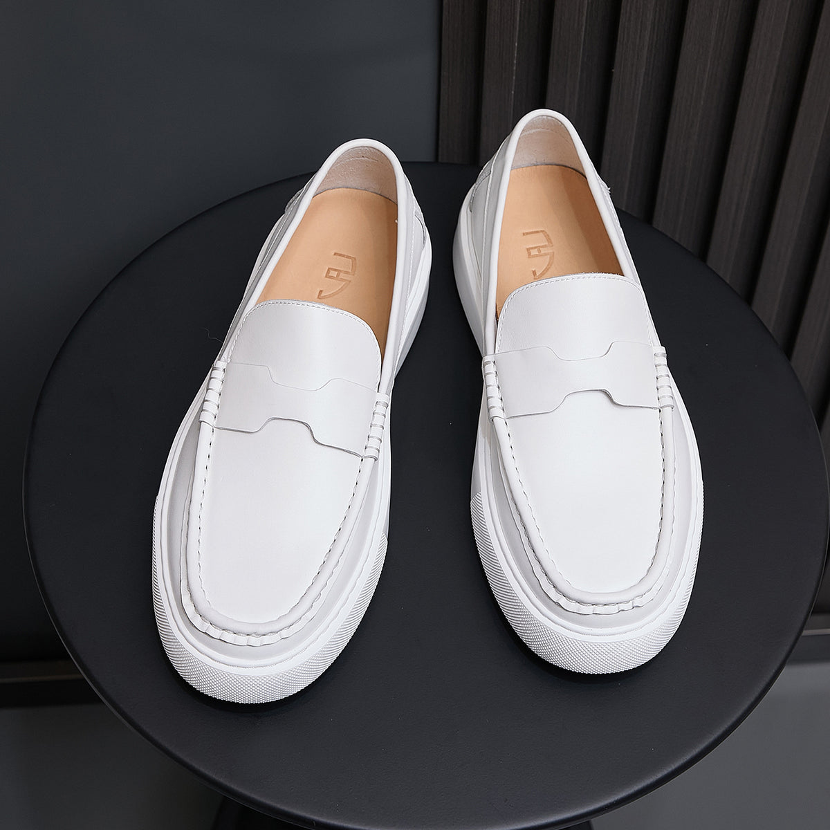 Men's white leather slip-on sneakers with white rubber sole and stitched moc toe panel.