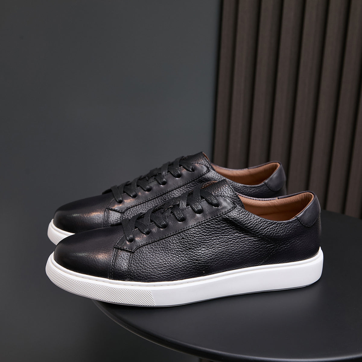 Black leather low-top sneakers with lace-up front and white rubber sole
