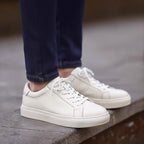 White leather low-top sneakers with lace-up closure and white rubber sole.