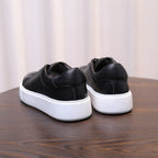 Black genuine leather sneakers with white rubber sole and low-profile side stitching.