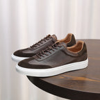 Men's leather sneakers in dark brown with lace-up front, suede panels, and white sole.