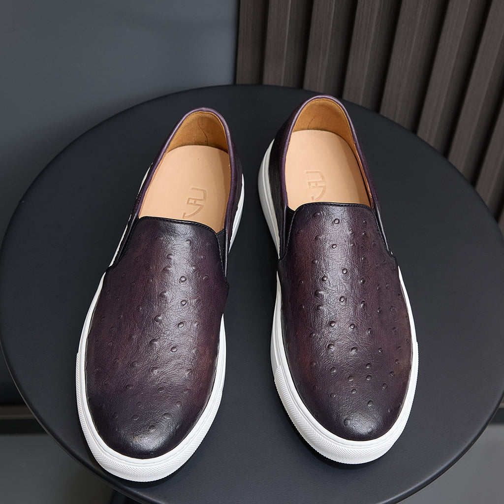 Pair of dark purple leather slip-on sneakers with perforations, tan lining, white sole