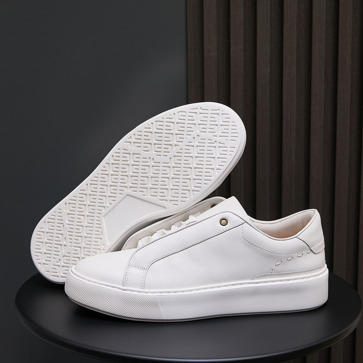 White leather sneakers with white outsole and textured tread pattern underside
