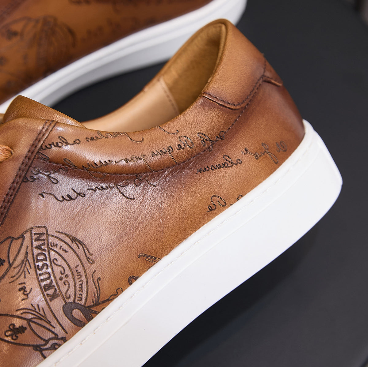 Men's tan leather sneakers close-up with padded collar and embossed lining