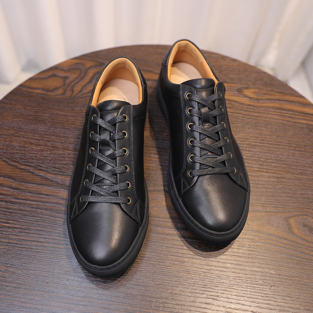 Pair of black leather lace-up sneakers with tan inner lining and cushioned collars.