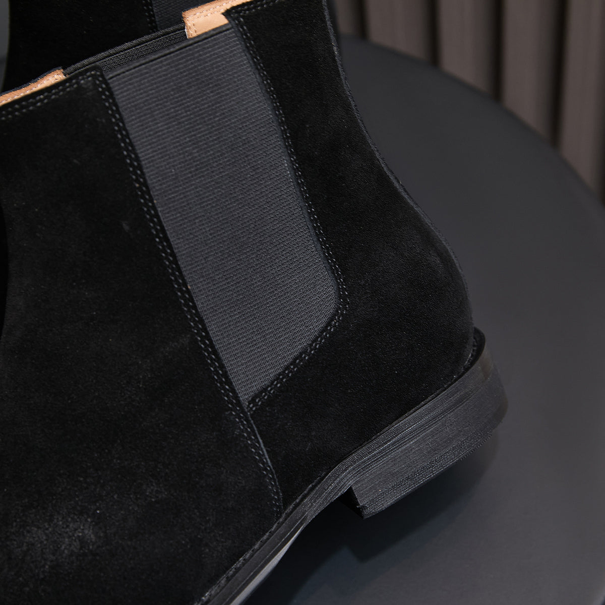 Side view of black suede Chelsea boot with elastic gore panel and low heel