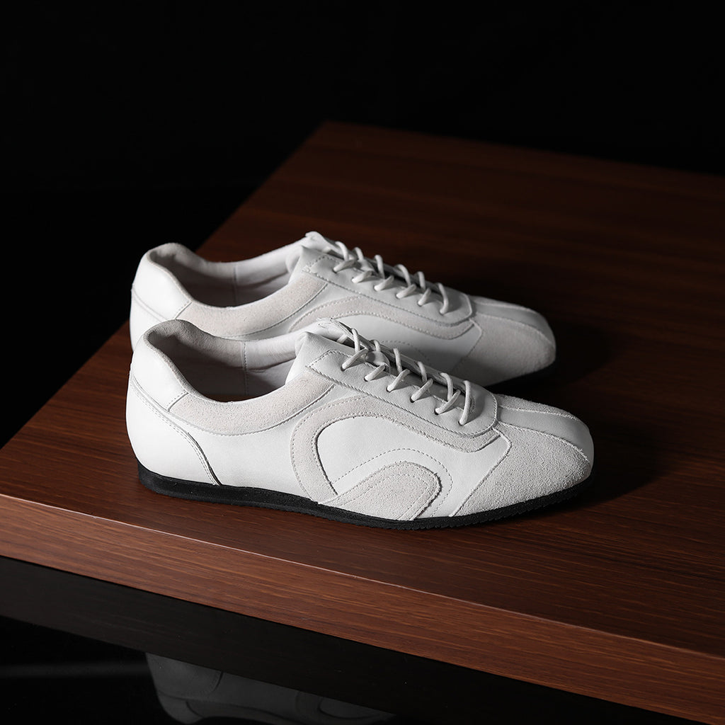 Pair of white leather low-top sneakers with lace-up closure and rounded toe.