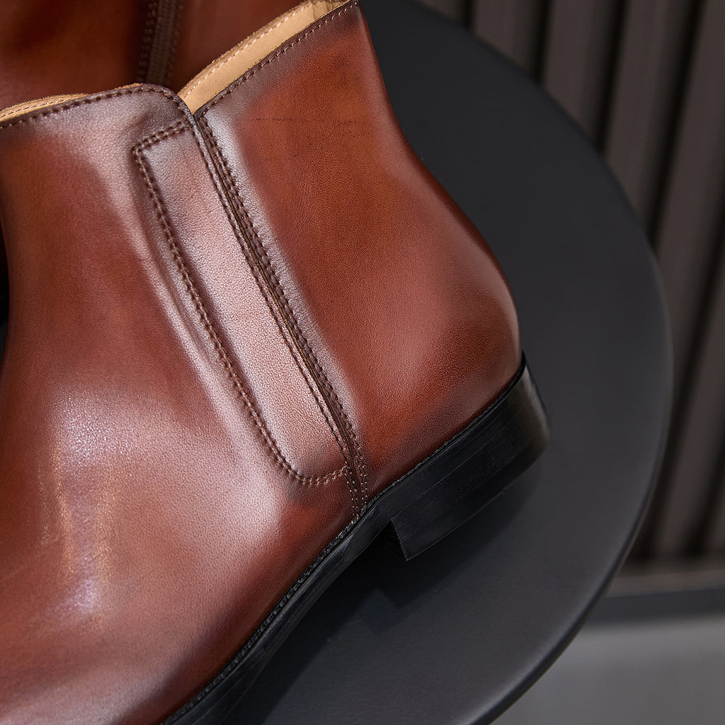 Brown leather dress boot with pointed cap toe and side zip, close-up