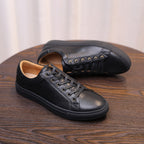 Black leather casual sneakers, side view showing lace-up design and stitched seams.