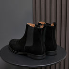 Back view of black suede Chelsea boots with elastic sides and pull tab loops