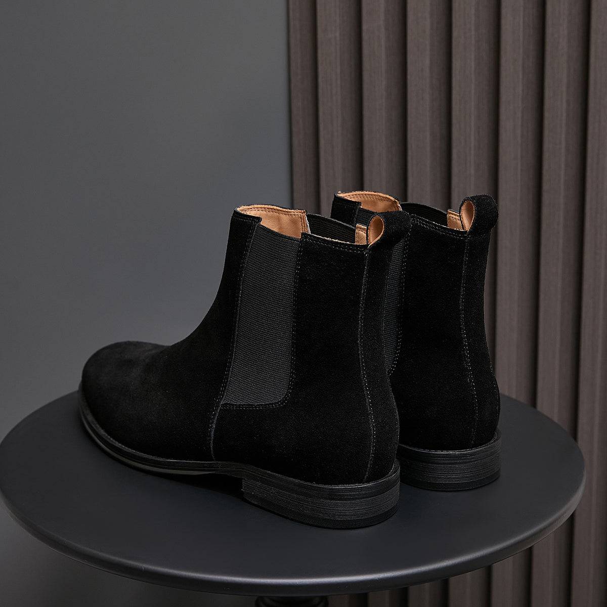 Back view of black suede Chelsea boots with elastic sides and pull tab loops