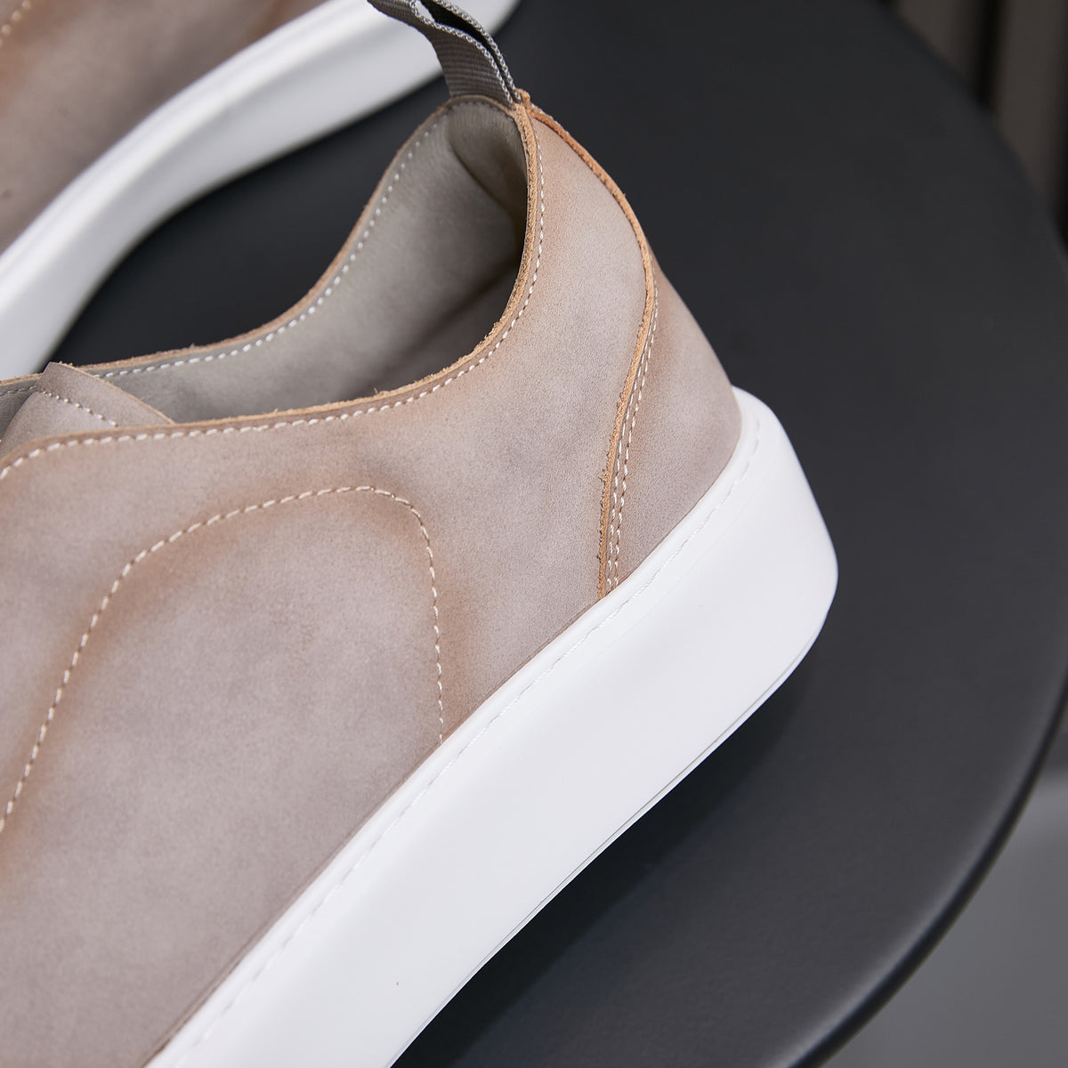 Tan/brown leather slip-on sneakers with stitched seams and white rubber sole.