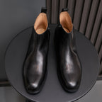 Black leather dress boots with pointed cap toe and side zip, front view pair